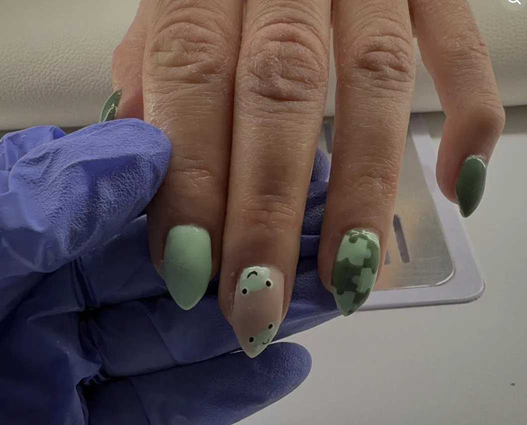 Sage green nails with a hand-painted check accent