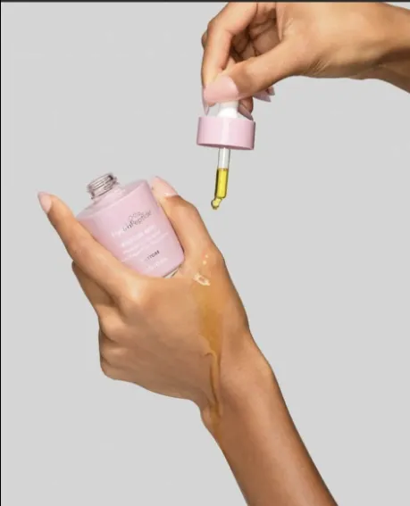 A pink HydroPeptide dropper bottle, with a drop on the back of the hand