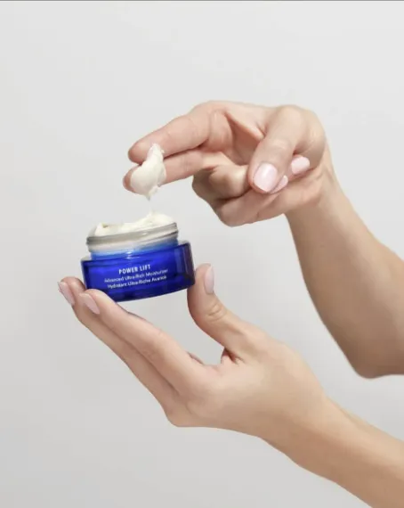 A hand holding an open jar of HydroPeptide Power Lift